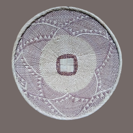 Round woven mat with geometric pattern on a wooden floor