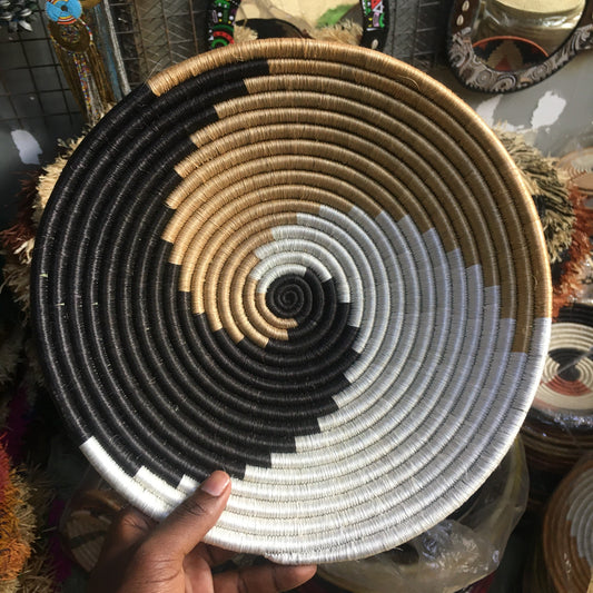 Handwoven basket with concentric circles held by a hand against a blurred background