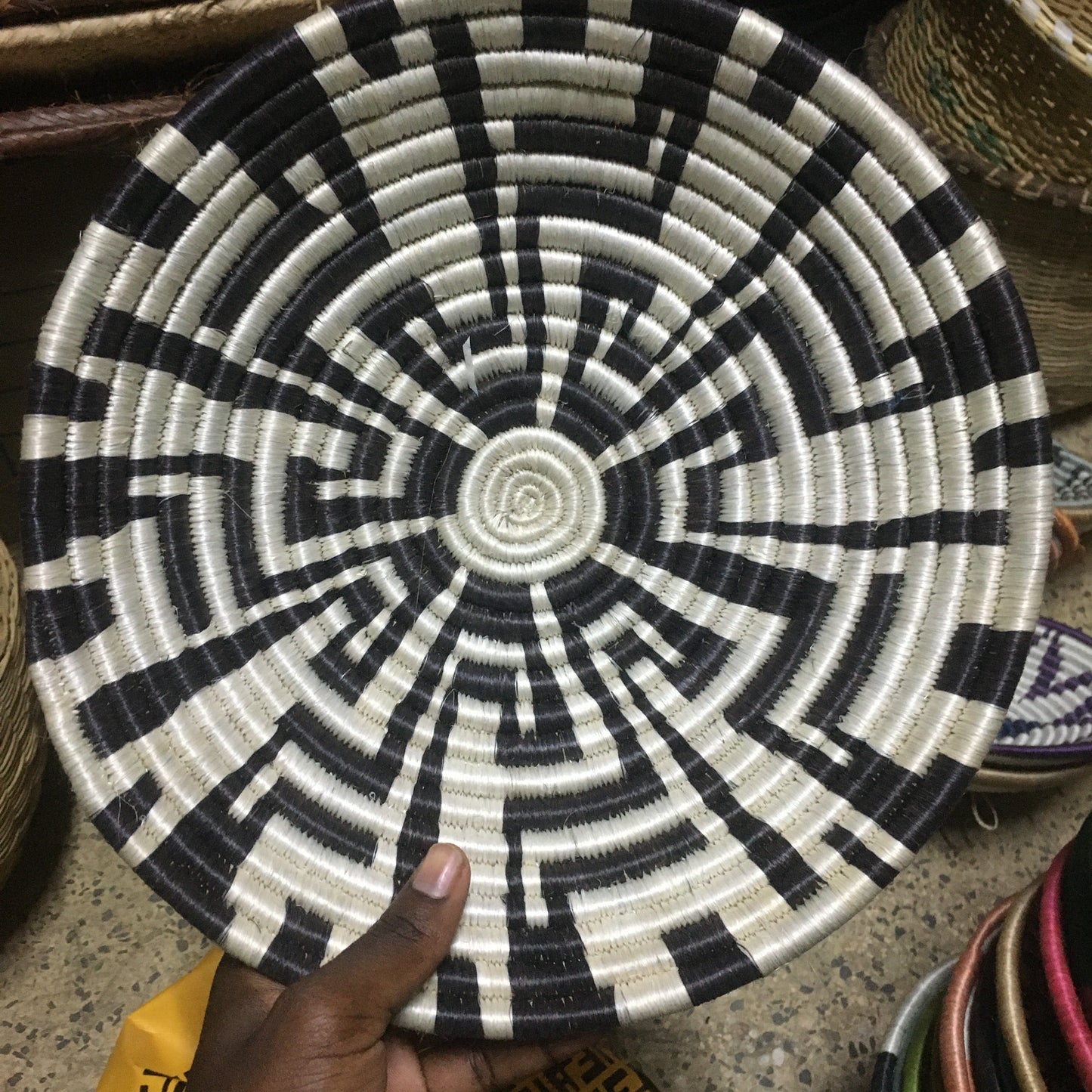 Black and white woven basket held by a hand on a textured surface