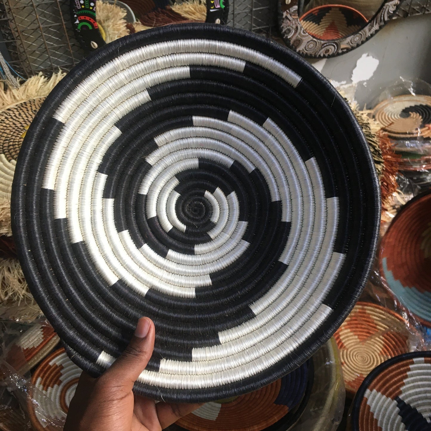Handheld woven basket with black and white pattern, surrounded by other decorative items.