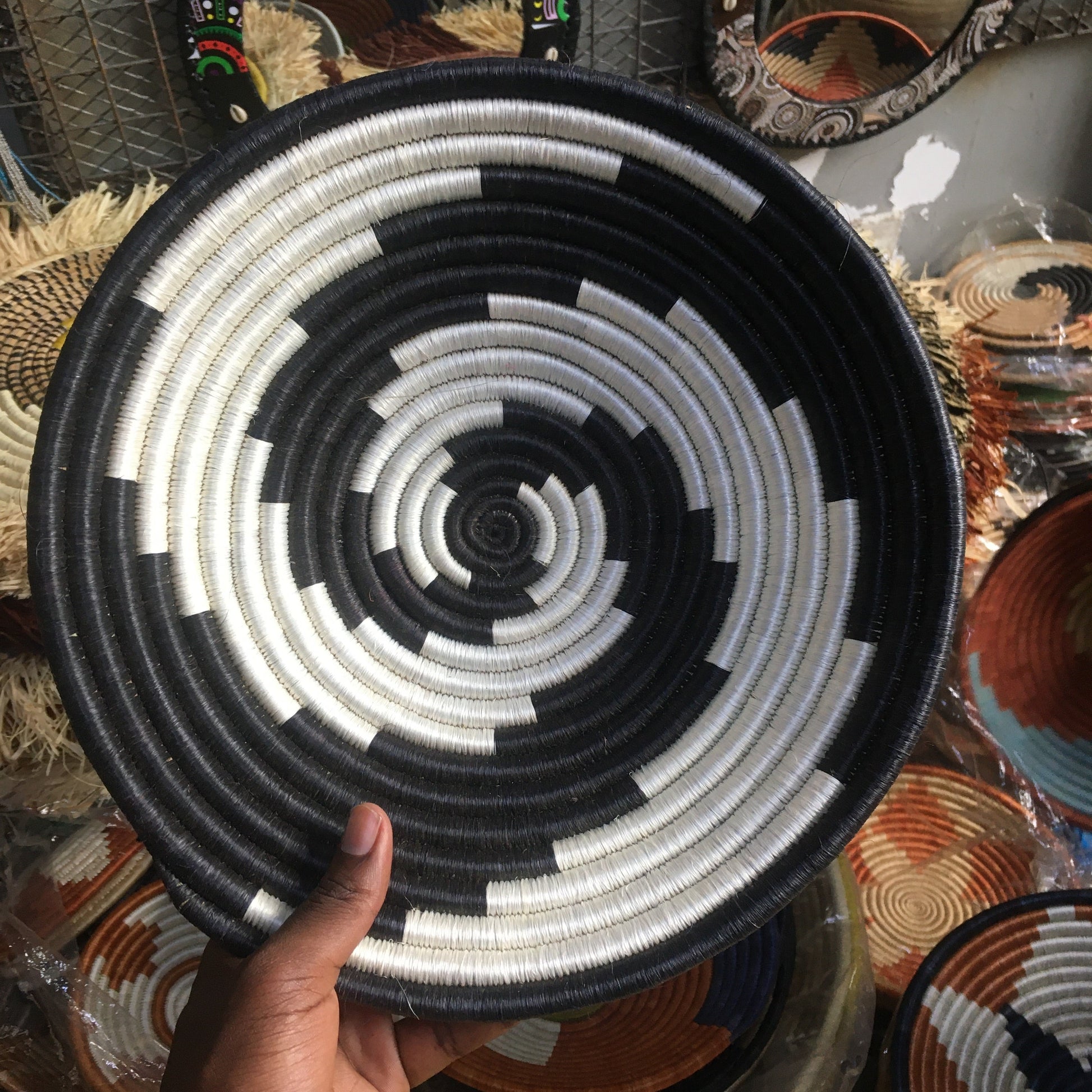 Handheld woven basket with black and white pattern, surrounded by other decorative items.