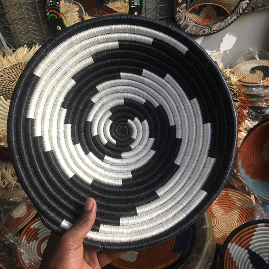 Handheld woven basket with black and white pattern, surrounded by other decorative items.